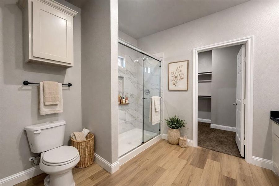Full bathroom with vanity, a walk in closet, a marble finish shower, and light wood finished floors