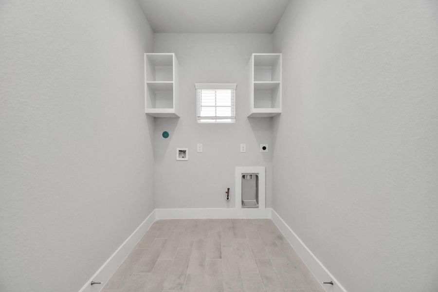 A perfect blend of functionality and comfort. Capture the essence of easy living with a first-floor laundry room, thoughtfully equipped with shelving for effortless organization. Both electric and gas connections available. Sample photo of completed home with similar floor plan. Actual colors and selections may vary.