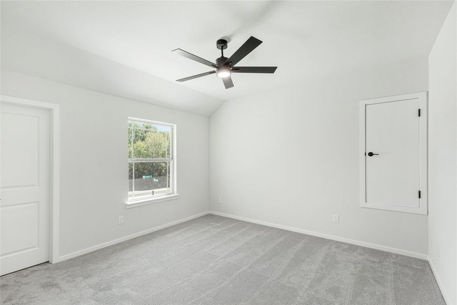 Empty bedroom with gray carpet, vaulted ceiling, black ceiling fan, and single window Empty bedroom with gray carpet, vaulted ceiling, black ceiling fan, and single window