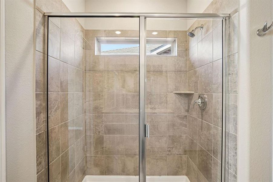 Full bathroom featuring a stall shower and a textured wall
