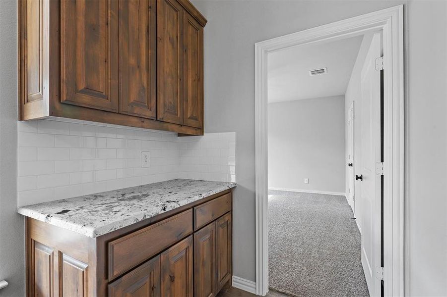 Kitchen featuring light stone counters, backsplash, and carpet