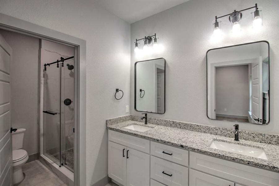 Bathroom with a stall shower, double vanity, and a textured wall Bathroom with a stall shower, double vanity, and a textured wall
