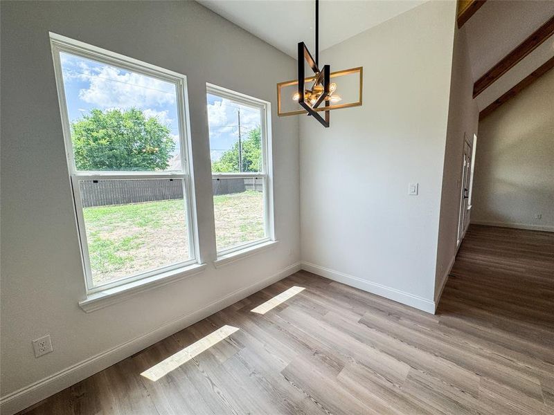 Unfurnished dining area with a chandelier, vaulted ceiling, baseboards, and light wood-style flooring Unfurnished dining area with a chandelier, vaulted ceiling, baseboards, and light wood-style flooring