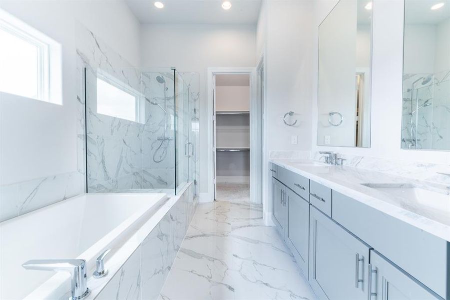 Pristine gray and whites along with a 6’ tub and a large shower with bench seat.