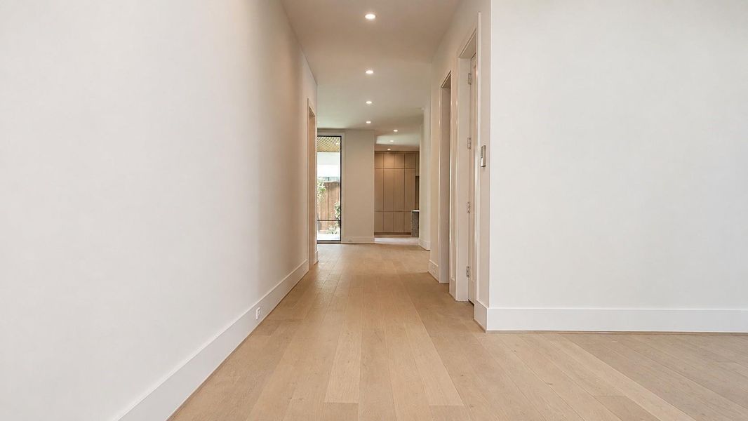 Entry hall with wide plank wood flooring, recessed lighting, and a direct sightline toward the main living areas.
