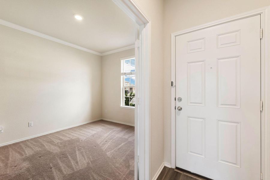 A welcoming entry, boasting a bright white door and wood-look flooring, opens to a carpeted interior space. A welcoming entry, boasting a bright white door and wood-look flooring, opens to a carpeted interior space.