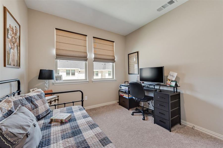 Bedroom featuring light colored carpet and a desk