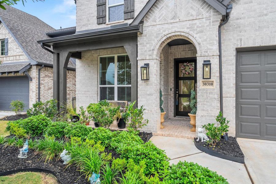 Built by Highland Homes, this beautiful residence showcases a classic brick elevation, lush landscaping, and a welcoming front porch that adds charm and timeless appeal.