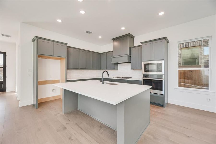 Kitchen featuring gray cabinetry, stainless steel appliances, light wood-type flooring, and recessed lighting