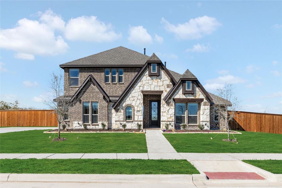 Two-story home with brick and stone exterior, arched entry, and manicured front lawn Two-story home with brick and stone exterior, arched entry, and manicured front lawn