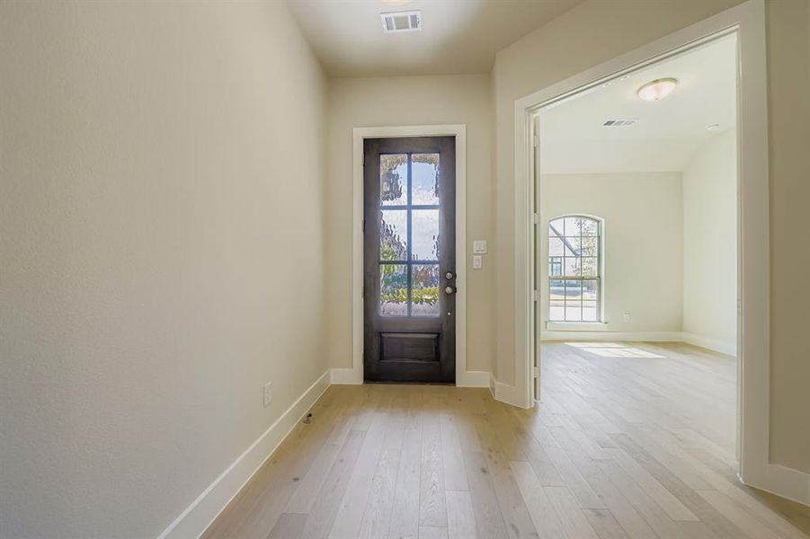 Doorway with hardwood / wood-style flooring and baseboards