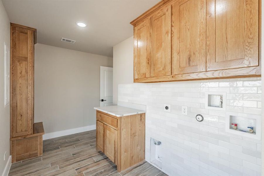 Laundry area with electric dryer hookup, cabinet space, washer hookup, wood finish floors, and recessed lighting Laundry area with electric dryer hookup, cabinet space, washer hookup, wood finish floors, and recessed lighting