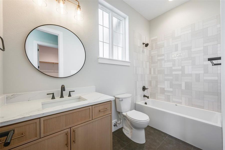 Bathroom with washtub / shower combination, vanity, and dark tile patterned floors
