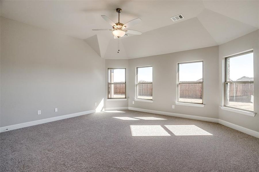 Carpeted empty room with ceiling fan and vaulted ceiling Carpeted empty room with ceiling fan and vaulted ceiling