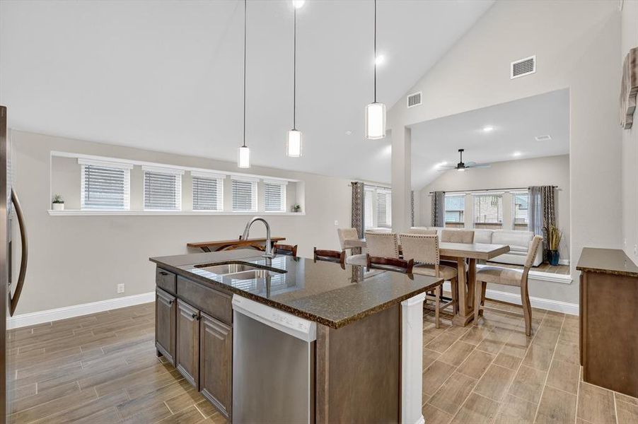 Kitchen island featuring a double-basin stainless steel sink, gooseneck faucet, and dark stone-finish countertop Kitchen island featuring a double-basin stainless steel sink, gooseneck faucet, and dark stone-finish countertop