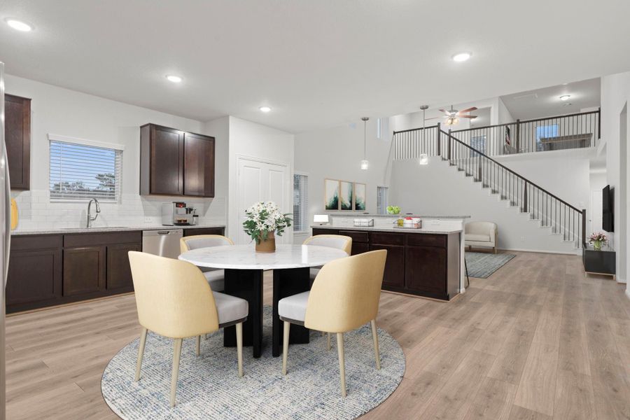 This virtually staged view shows how beautifully the dining area flows into the family room, keeping everyone connected while still offering defined spaces for dining and relaxation. The open-concept design makes entertaining effortless.  Look at the stunning view of the dramatic family area!    Wonderful tile like wood floors throughout, less upkeep!