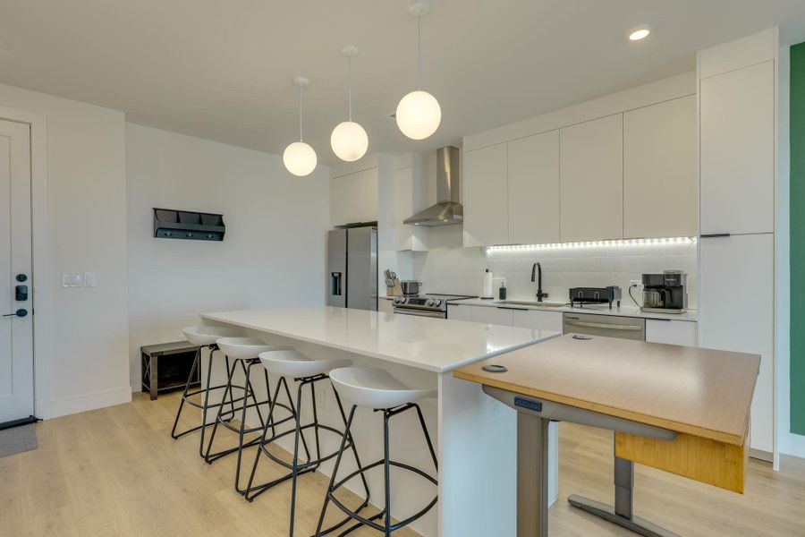 The kitchen features white cabinetry, stainless steel appliances, and a large island with seating