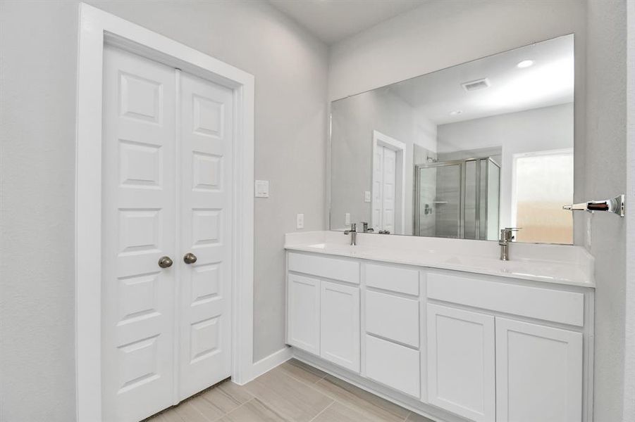 Delight in a spacious walk-in shower enveloped in stylish tile surround, unwind in a separate garden tub adorned with custom detailing, and elevate your daily routine at the elegant vanity, now equipped with double sinks, light countertops, modern hardware.