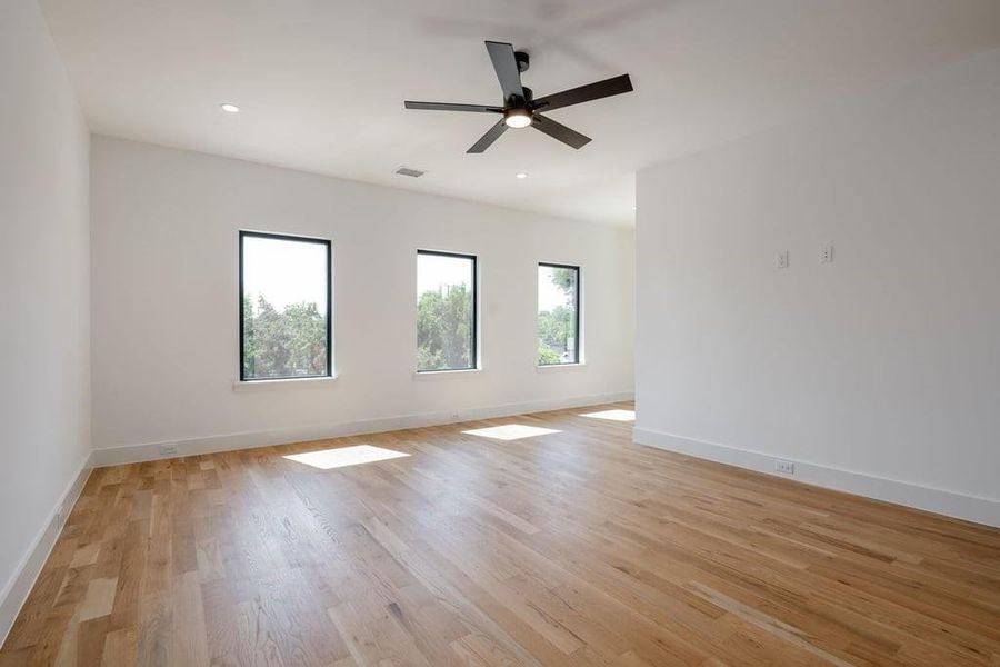 Primary 2 bedroom with sitting area, hardwood flooring and ceiling fan