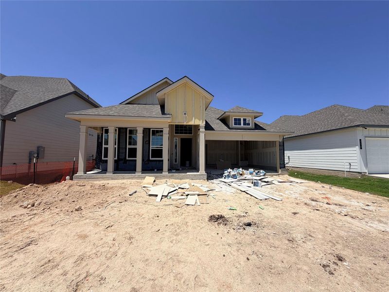 A newly constructed residence awaits finishing touches, featuring a welcoming covered entry and an attached garage.