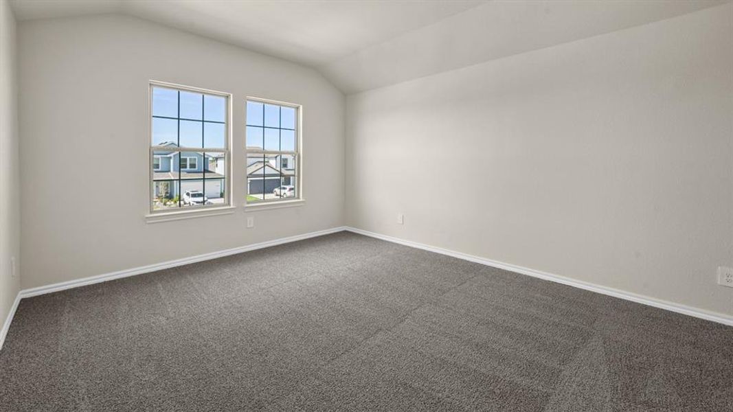 Spacious room featuring vaulted ceilings, light neutral wall paint, and gray carpeting