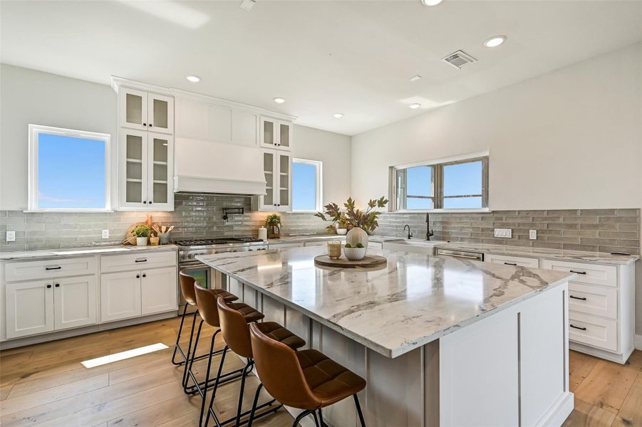 The kitchen was designed for connection with expansive island seating and seamless flow into the living and dining spaces. Quartz countertops, custom cabinetry, and luxury finishes elevate every moment spent here.