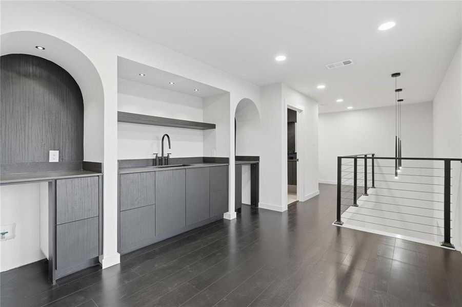 Second-story landing featuring a wet bar with dark cabinetry, integrated sink, and matte black faucet