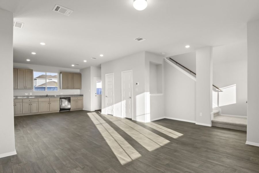 Image of a living room with a staircase leading upstairs and a open layout kitchen