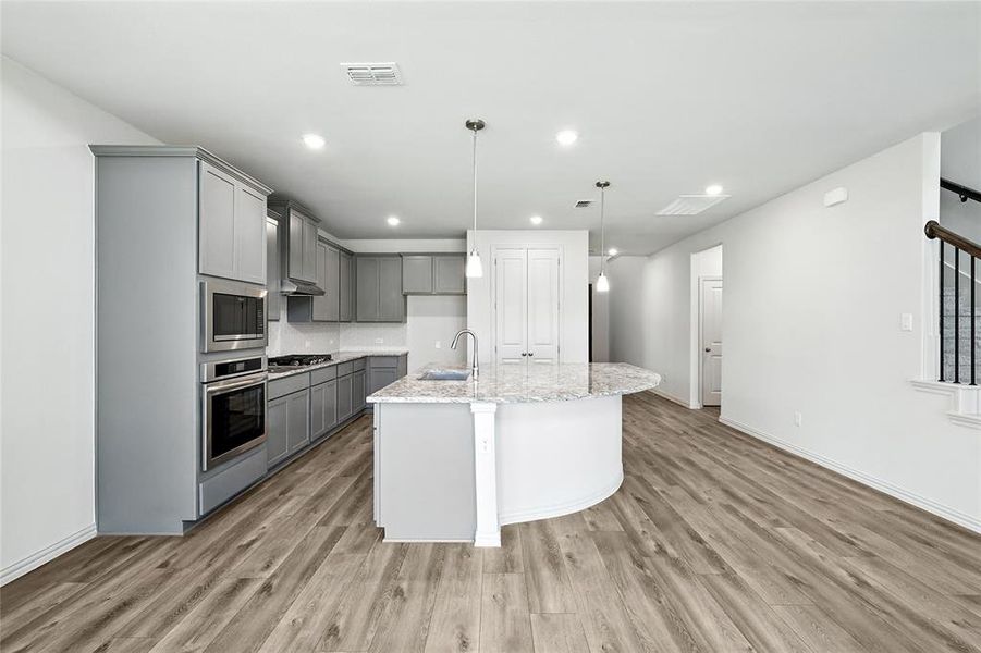 Kitchen featuring gray cabinetry, appliances with stainless steel finishes, light wood-style floors, light stone countertops, and recessed lighting Kitchen featuring gray cabinetry, appliances with stainless steel finishes, light wood-style floors, light stone countertops, and recessed lighting