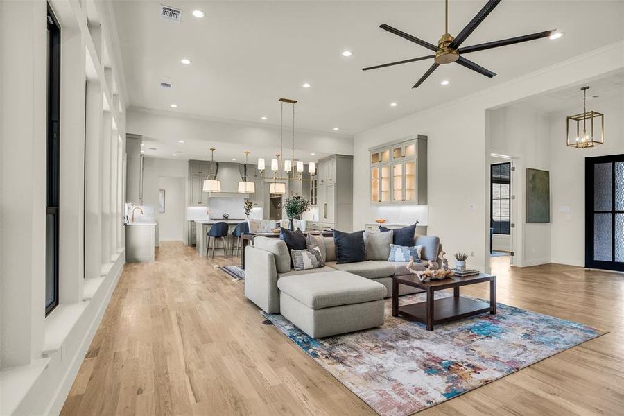 Living room featuring a chandelier, ornamental molding, recessed lighting, light wood finished floors, and ceiling fan Living room featuring a chandelier, ornamental molding, recessed lighting, light wood finished floors, and ceiling fan
