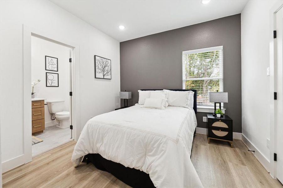 The additional secondary bedroom features wood-look LVP flooring, recessed lighting, and a large window that fills the room with natural light.