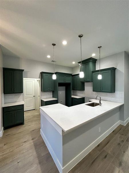 Kitchen featuring wood-type flooring, hanging light fixtures, and sink