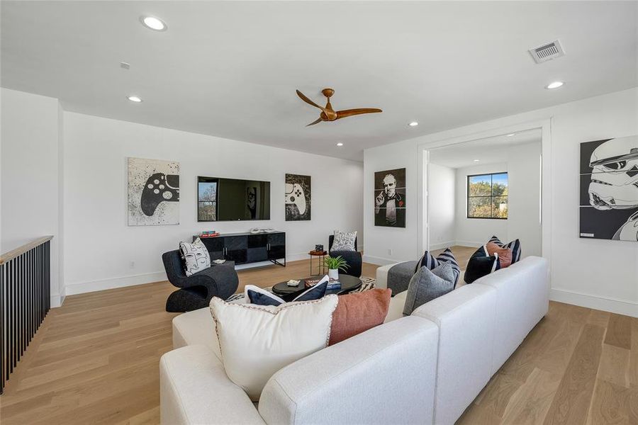 Spacious open room featuring wood-finish flooring, recessed lighting, and a contemporary ceiling fan