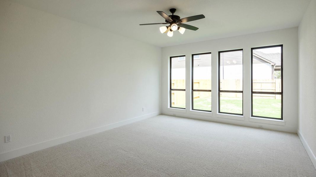 Carpeted empty room featuring baseboards and ceiling fan