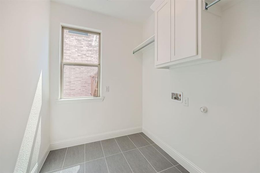 Laundry room featuring washer hookup, tile patterned floors, and cabinets