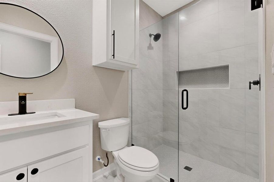Bathroom with vanity, a shower stall, and a textured wall Bathroom with vanity, a shower stall, and a textured wall