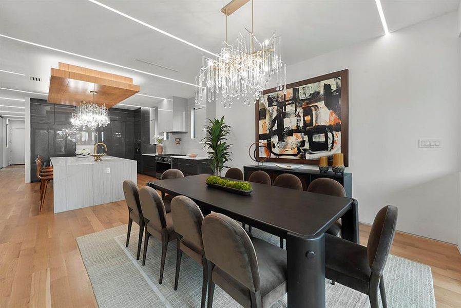 Open concept living space featuring wood-finish flooring, recessed linear lighting, and a crystal chandelier