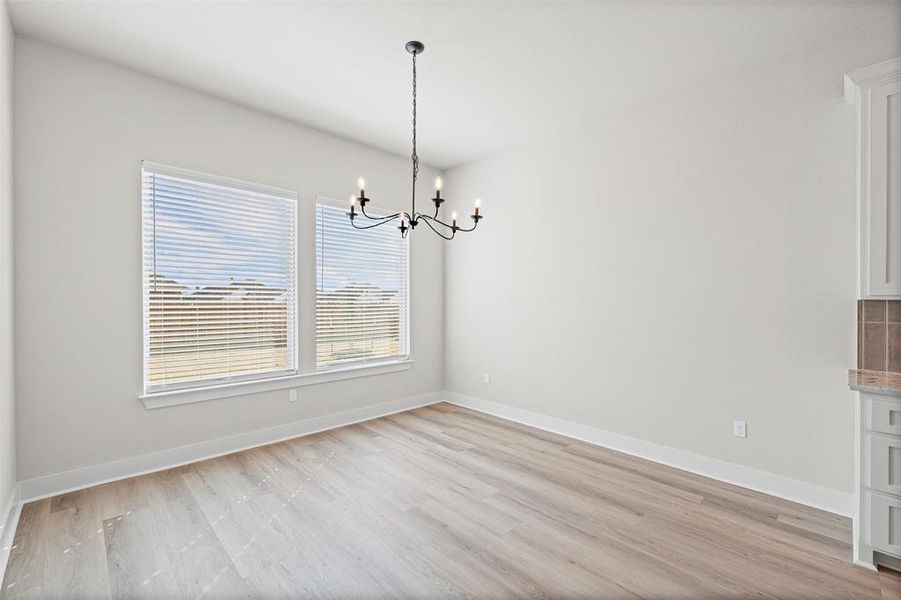 Unfurnished dining area featuring a chandelier and light wood-type flooring