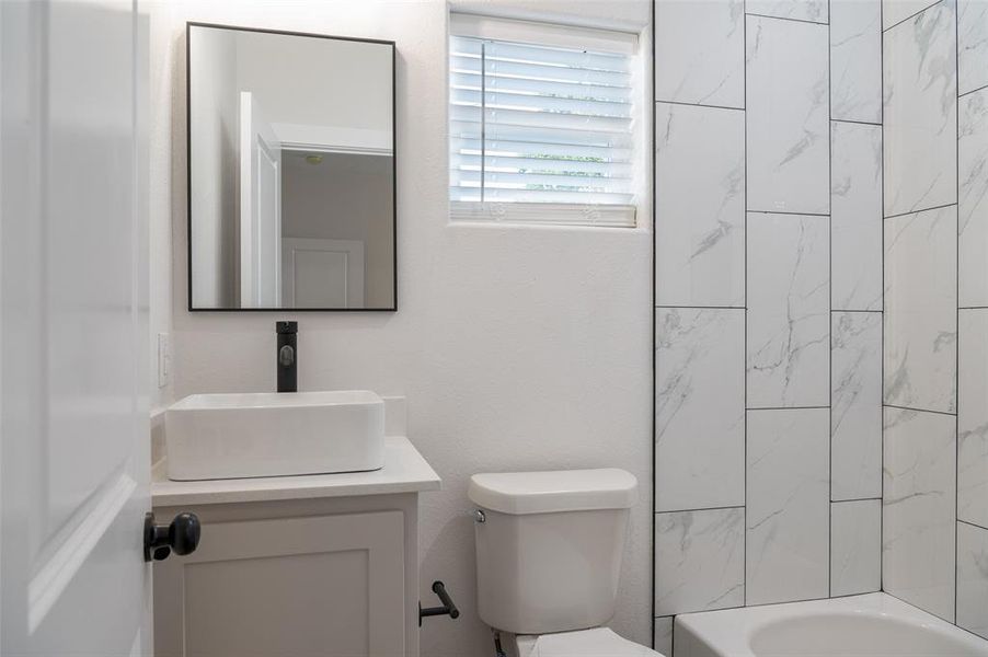 Full bathroom with toilet, vanity, and tiled shower / bath