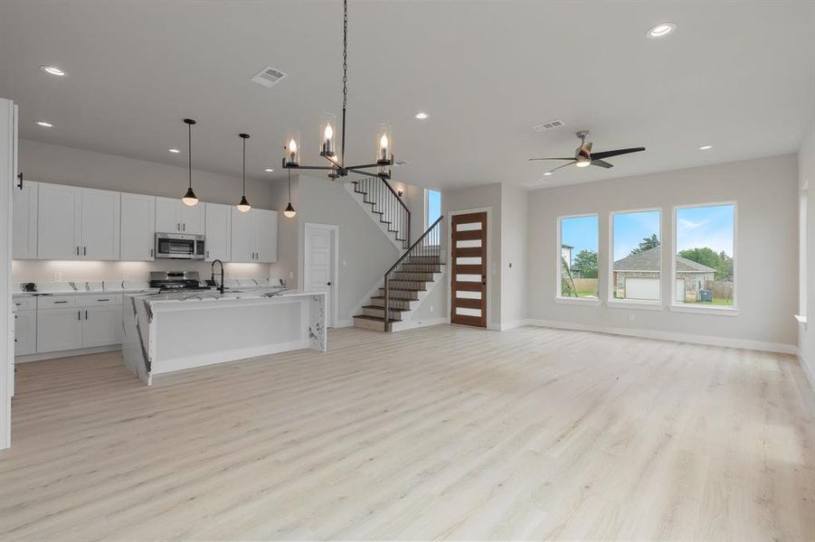 Kitchen with stainless steel appliances, open floor plan, recessed lighting, light wood finished floors, and a center island with sink