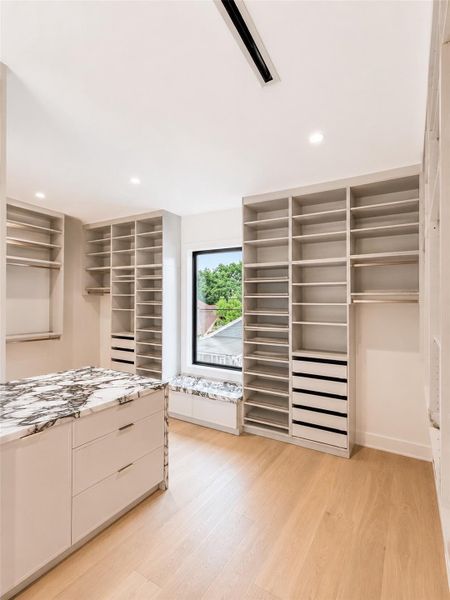 Primary closet includes build in shelves, drawer, and hanging space.