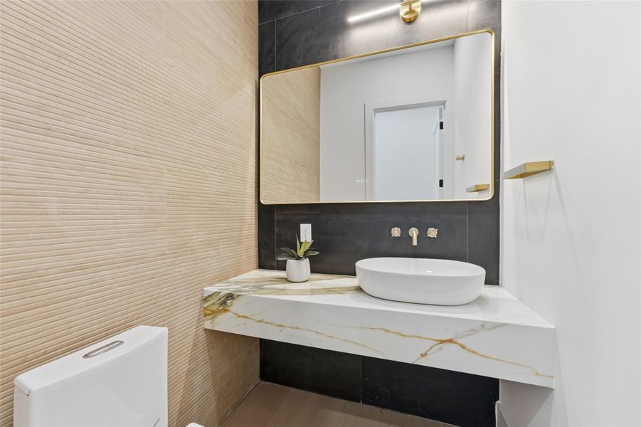 A private, tucked-away powder room with a floating vanity, dramatic mirror, and refined finishes