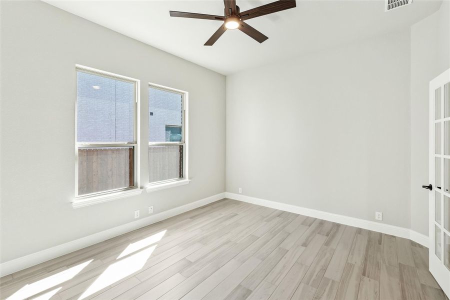 Empty room with light wood floors, ceiling fan, two windows, and white walls Empty room with light wood floors, ceiling fan, two windows, and white walls