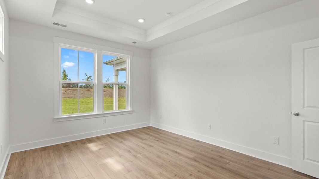 Primary suite highlights include backyard views, tray ceiling, and elegant wood flooring. Primary suite highlights include backyard views, tray ceiling, and elegant wood flooring.