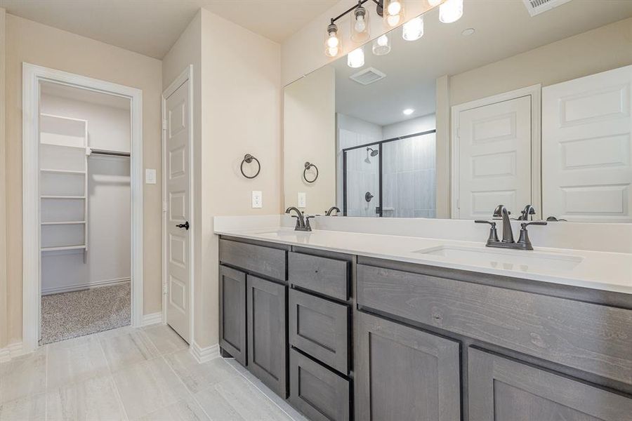 Bathroom with a shower with door, vanity, and tile patterned floors