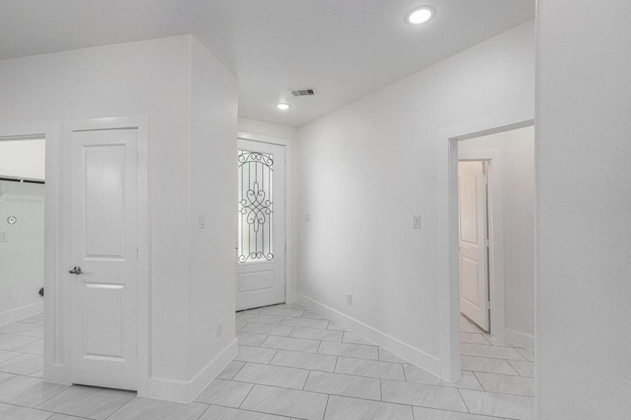Bright entryway featuring white walls and tile flooring, with elegant decorative door glass and modern recessed lighting. Bright entryway featuring white walls and tile flooring, with elegant decorative door glass and modern recessed lighting.