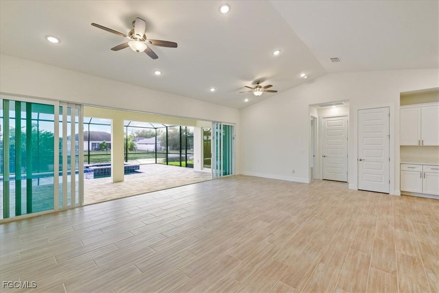 Spare room featuring wood finish floors, lofted ceiling, ceiling fan, and recessed lighting