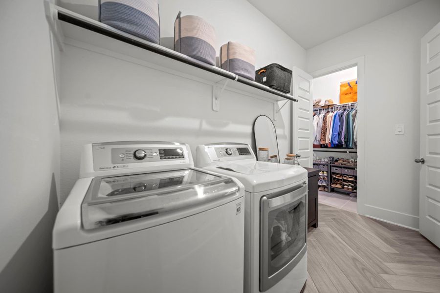 Functional laundry space with full-size washer and dryer hookups, storage shelf, and direct access to the primary closet. Functional laundry space with full-size washer and dryer hookups, storage shelf, and direct access to the primary closet.