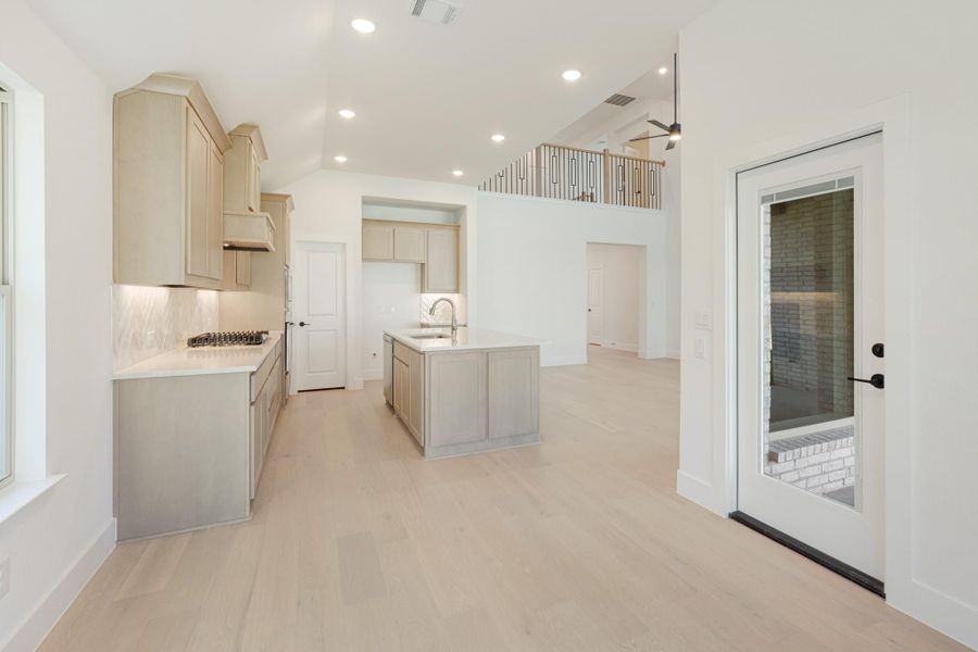 Open kitchen with light wood cabinets, center island, and hardwood floors in a two-story home