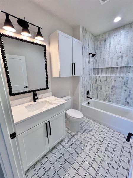 Guest bathroom featuring tasteful and decorative tile, framed mirror and matte black fixtures.